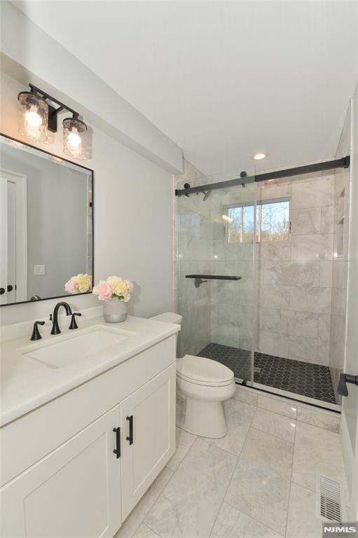 bathroom with vanity, a shower with door, and toilet