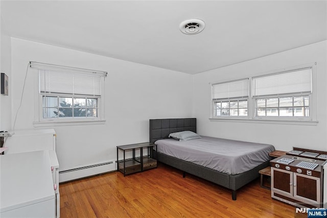 bedroom with multiple windows, light hardwood / wood-style flooring, and a baseboard radiator