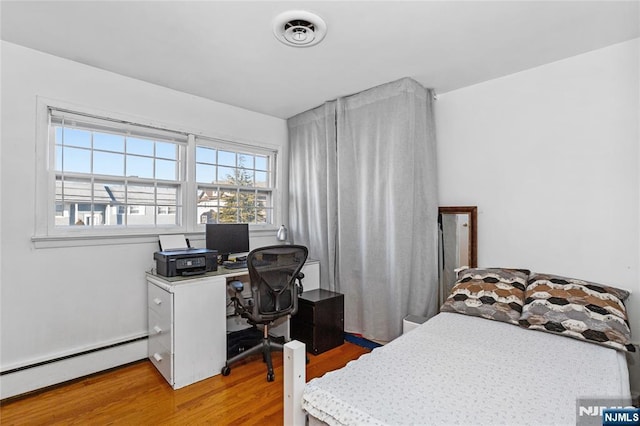 bedroom with wood-type flooring and baseboard heating