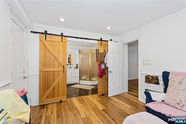 living area with hardwood / wood-style flooring, ornamental molding, a barn door, and sink