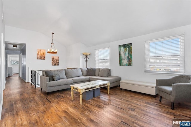 living room featuring vaulted ceiling, dark hardwood / wood-style floors, and an inviting chandelier