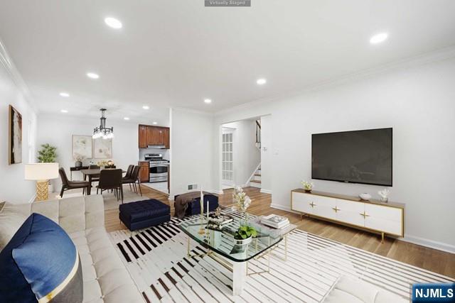 living room featuring crown molding, a chandelier, and light hardwood / wood-style floors