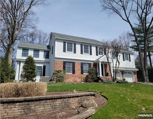 view of front facade with a garage, brick siding, and a front lawn