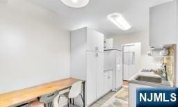 kitchen with white cabinetry and white refrigerator with ice dispenser