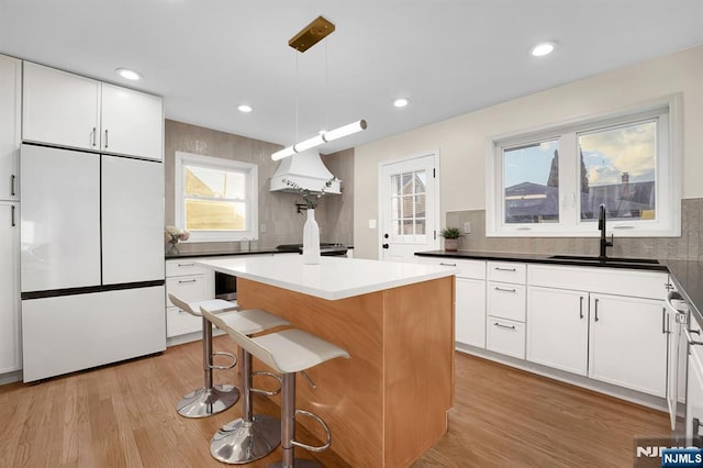 kitchen with sink, white cabinets, a kitchen island, decorative light fixtures, and built in fridge