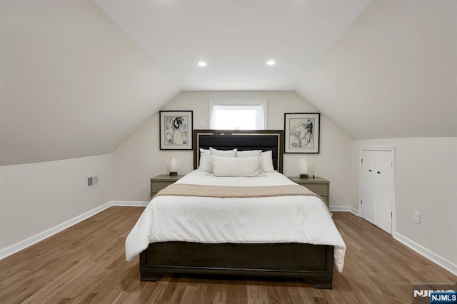 bedroom with hardwood / wood-style flooring and lofted ceiling