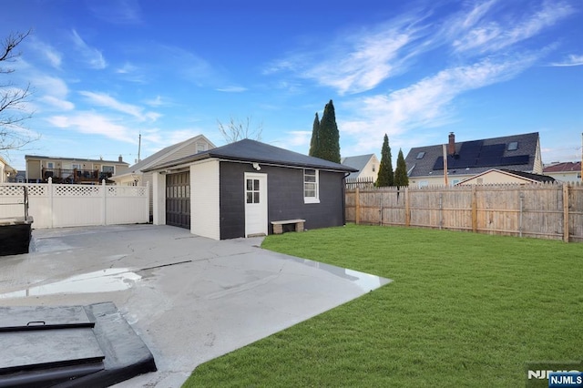 back of house featuring a yard, an outdoor structure, and a patio area