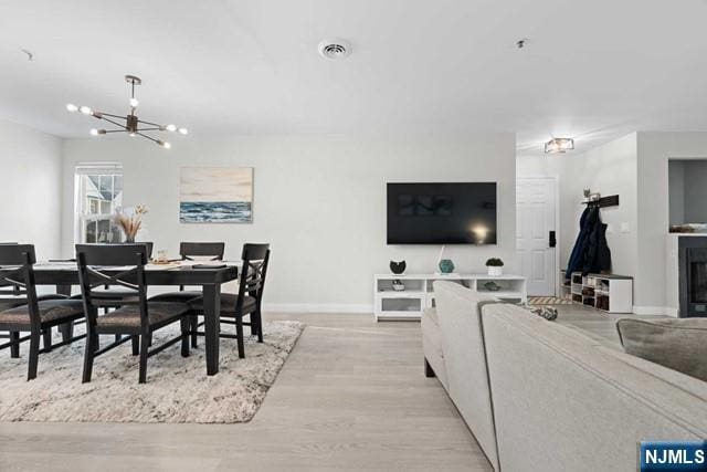 dining room with light wood-type flooring and an inviting chandelier