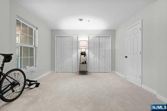 interior space featuring light carpet and two closets