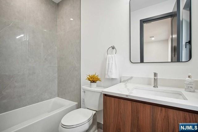 full bathroom featuring vanity, tiled shower / bath, and toilet