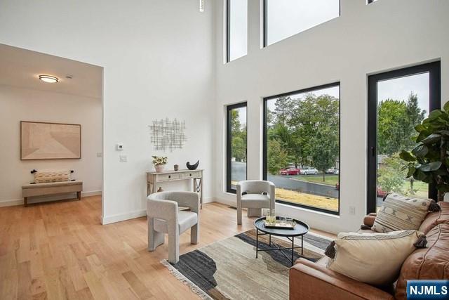 living area featuring a towering ceiling and light hardwood / wood-style floors