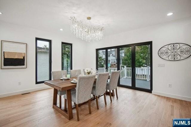 dining space with an inviting chandelier and light hardwood / wood-style flooring