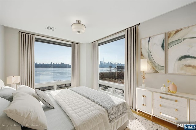 bedroom featuring a water view, wood-type flooring, and multiple windows