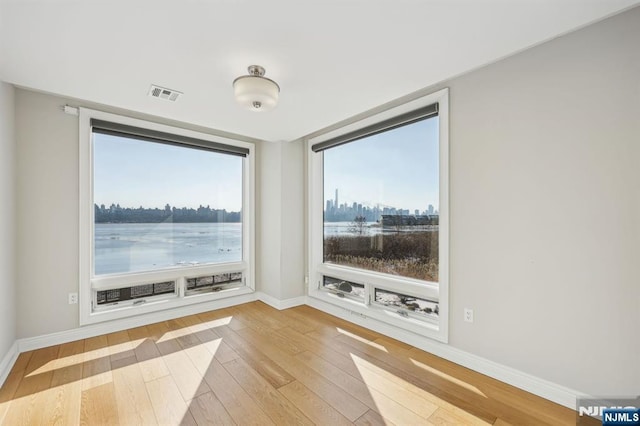 unfurnished room featuring a water view, plenty of natural light, and light wood-type flooring