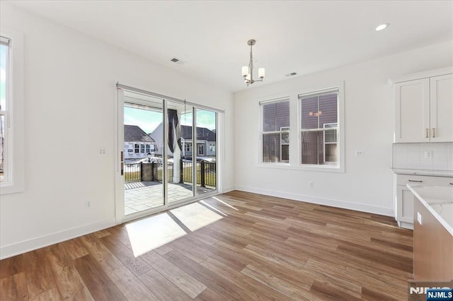 unfurnished dining area with a notable chandelier and light hardwood / wood-style floors