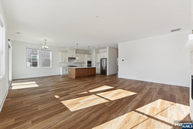 unfurnished living room featuring an inviting chandelier and dark hardwood / wood-style flooring