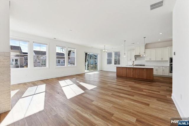 unfurnished living room with sink and light wood-type flooring