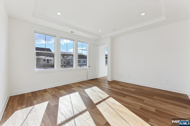 empty room featuring a raised ceiling and hardwood / wood-style flooring