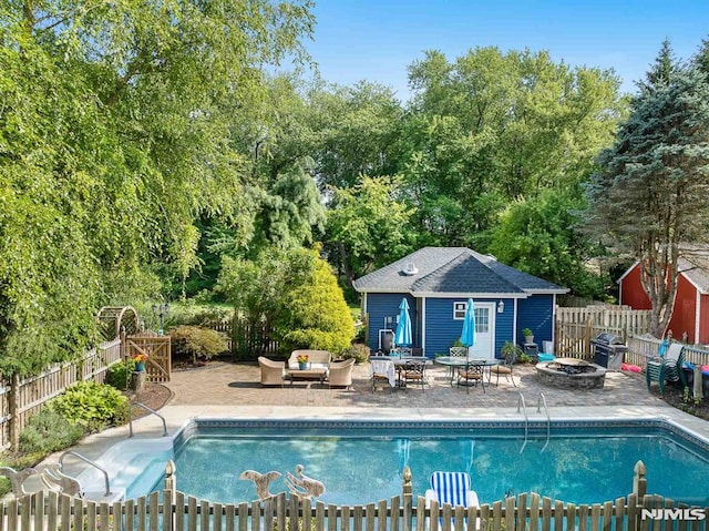 view of swimming pool with an outdoor living space with a fire pit, a grill, an outbuilding, and a patio area