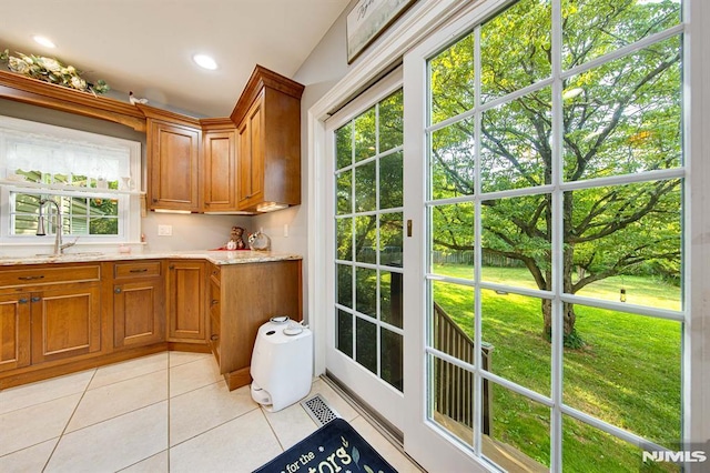 kitchen featuring light stone countertops, sink, light tile patterned floors, and plenty of natural light