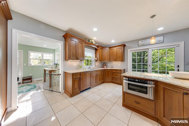 kitchen featuring pendant lighting, stainless steel oven, light tile patterned flooring, and sink