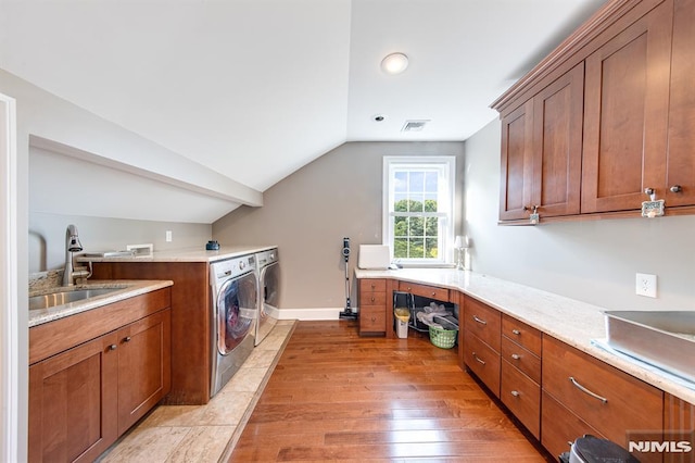 washroom with sink, hardwood / wood-style floors, cabinets, and washer and dryer