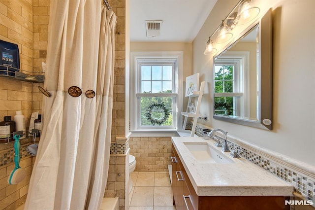 bathroom featuring vanity, toilet, tile walls, and a healthy amount of sunlight