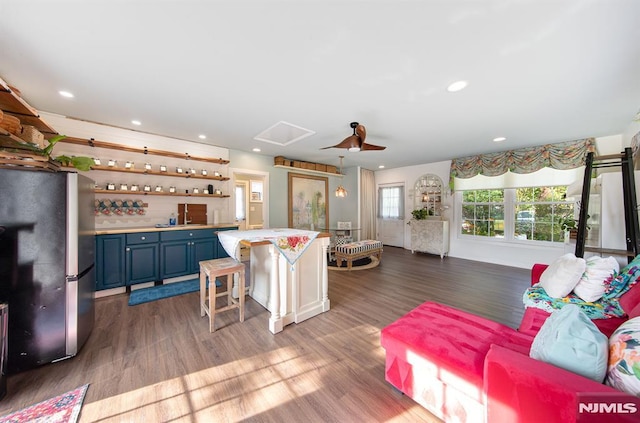 kitchen with stainless steel refrigerator, wood-type flooring, blue cabinets, and a breakfast bar area