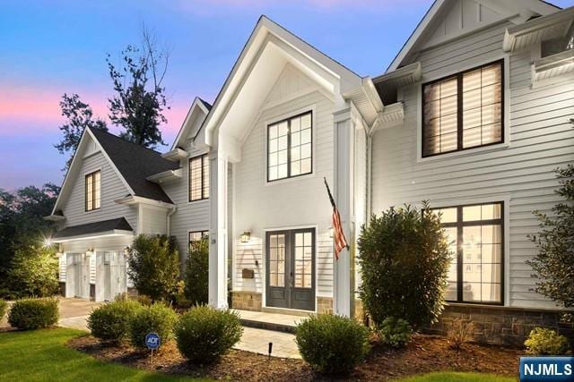 back house at dusk with a lawn and french doors