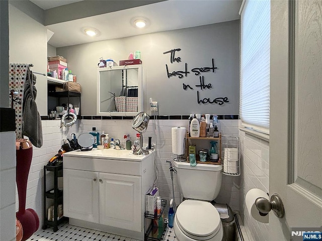 bathroom featuring vanity, toilet, and tile walls