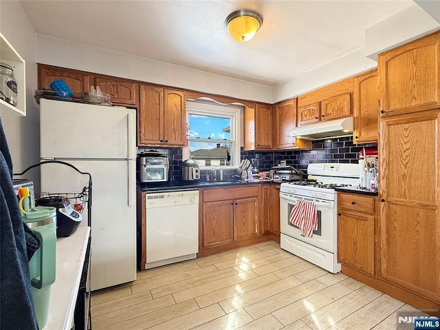 kitchen featuring sink, white appliances, light hardwood / wood-style floors, and decorative backsplash