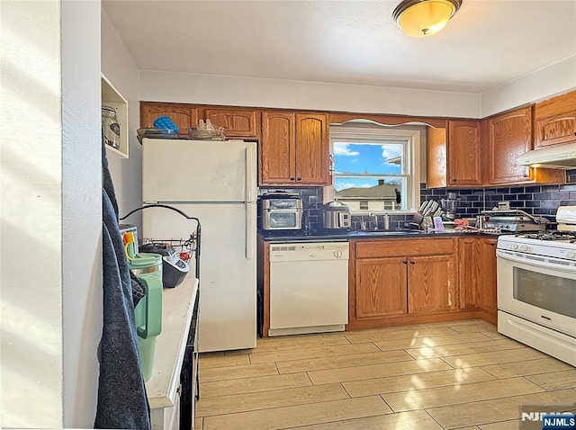 kitchen with sink, backsplash, white appliances, and light hardwood / wood-style flooring