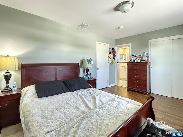 bedroom featuring dark hardwood / wood-style floors, ensuite bath, and a closet