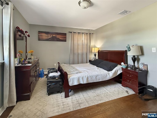 bedroom featuring light hardwood / wood-style flooring and a baseboard heating unit