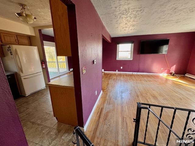 unfurnished living room with light hardwood / wood-style flooring and a textured ceiling