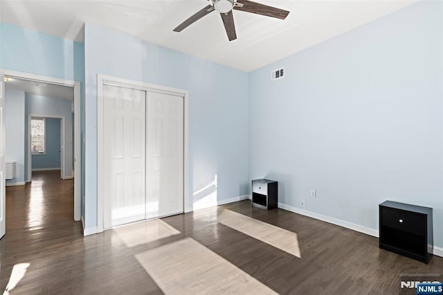 bedroom with dark wood-type flooring, ceiling fan, and a closet