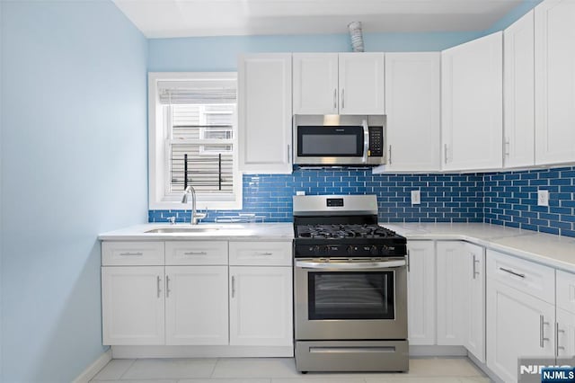 kitchen with white cabinetry, appliances with stainless steel finishes, sink, and backsplash