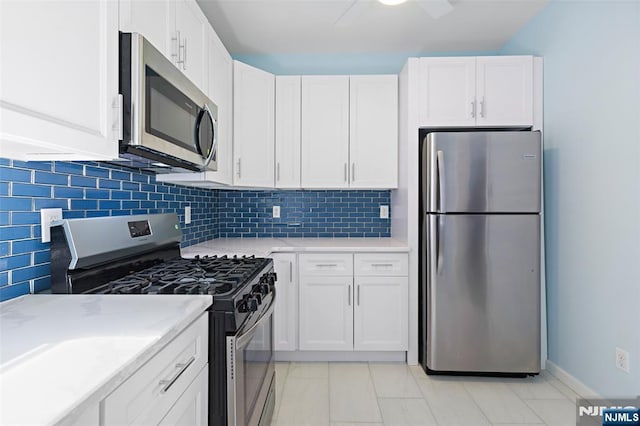 kitchen featuring light stone countertops, white cabinetry, appliances with stainless steel finishes, and backsplash