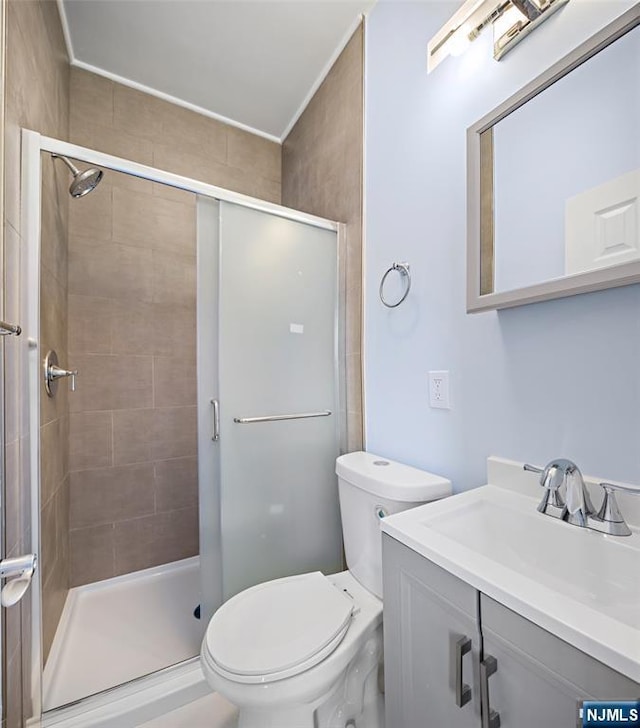 bathroom featuring vanity, a shower with door, and toilet