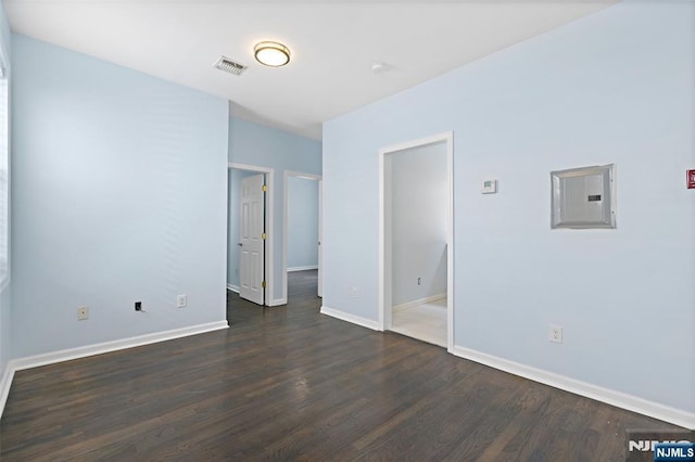 empty room with electric panel and dark hardwood / wood-style floors