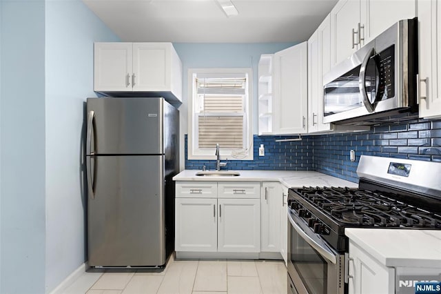 kitchen with light stone counters, stainless steel appliances, sink, and white cabinets