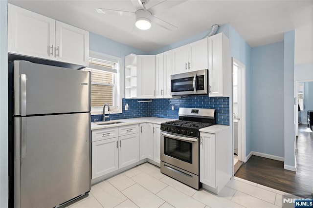 kitchen with tasteful backsplash, appliances with stainless steel finishes, sink, and white cabinets