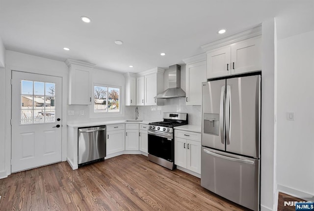 kitchen featuring dark wood-type flooring, sink, white cabinetry, appliances with stainless steel finishes, and wall chimney range hood