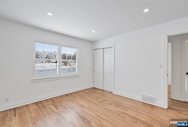 unfurnished bedroom with a closet and light wood-type flooring