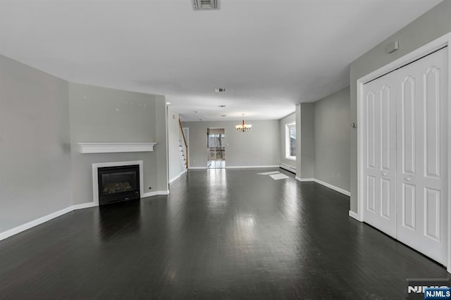 unfurnished living room with a glass covered fireplace, a notable chandelier, baseboards, and wood finished floors