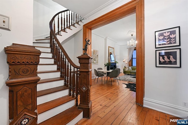 stairs with crown molding, a chandelier, and hardwood / wood-style floors