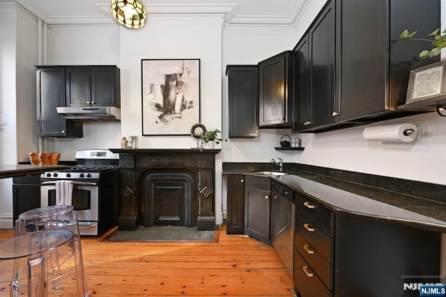 kitchen with sink, dark stone counters, ornamental molding, stainless steel appliances, and light hardwood / wood-style flooring