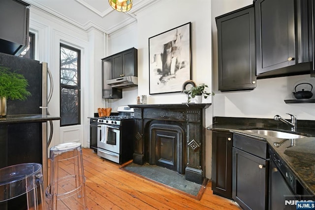 kitchen featuring sink, crown molding, appliances with stainless steel finishes, dark stone counters, and light wood-type flooring