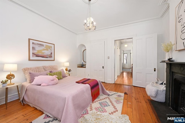 bedroom with crown molding, hardwood / wood-style floors, and an inviting chandelier