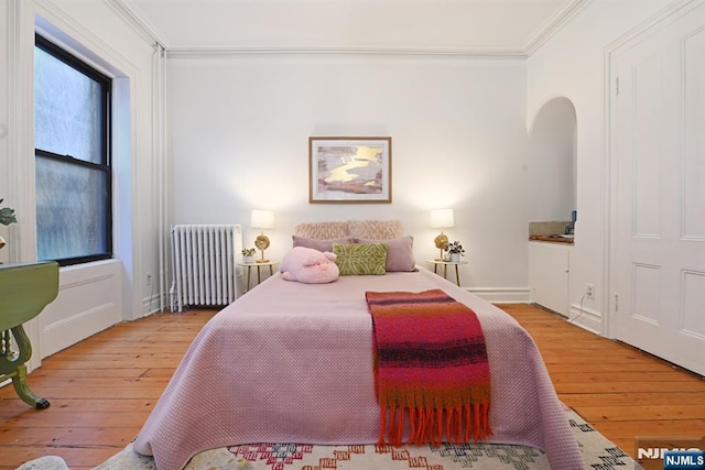 bedroom featuring crown molding, radiator heating unit, and hardwood / wood-style flooring